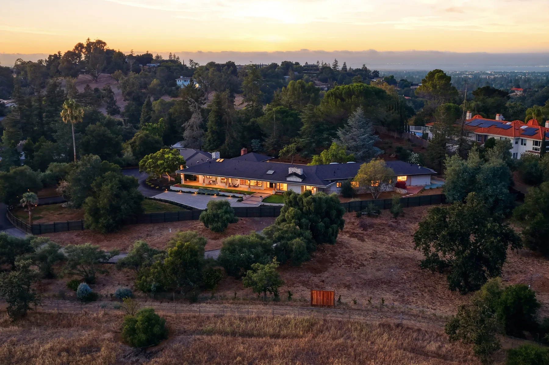 Aerial photograph of a hillside home at sunset.