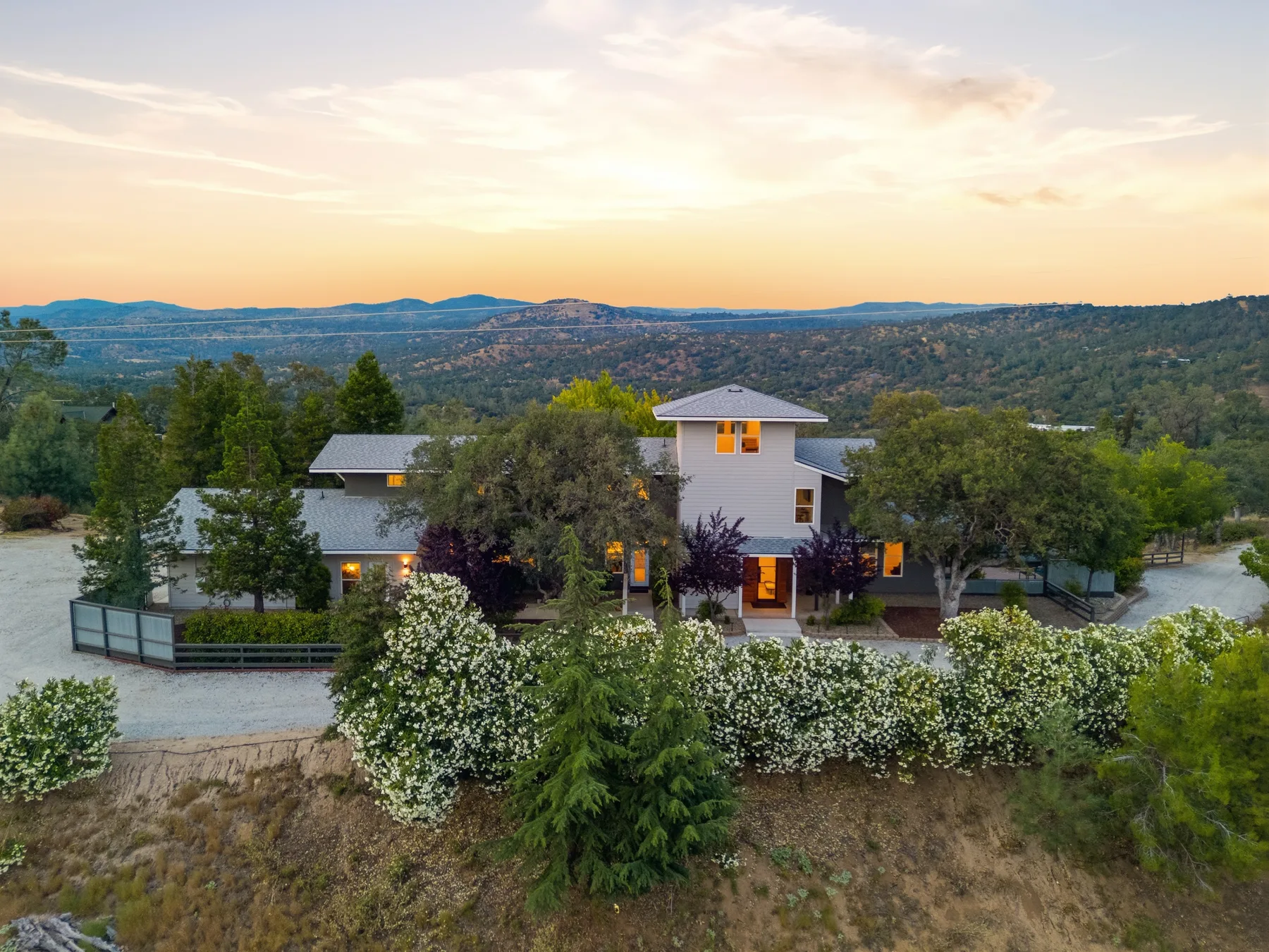 Aerial photograph of a modern home among trees at sunset.