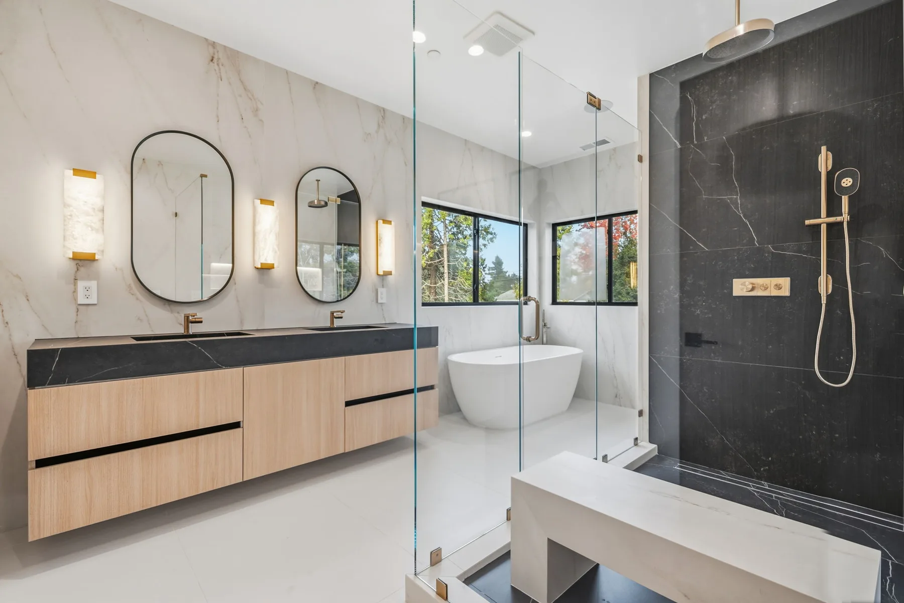 Bright modern bathroom with a double vanity, glass shower, and freestanding tub.