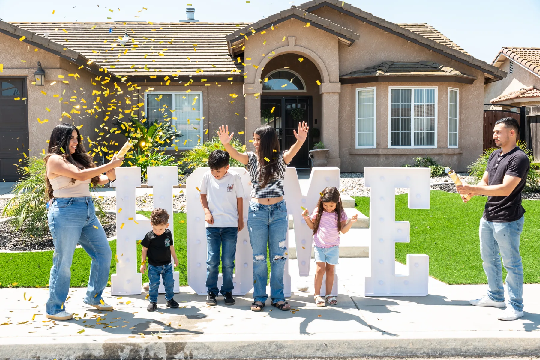 Group tosses confetti beside a HOME sign.