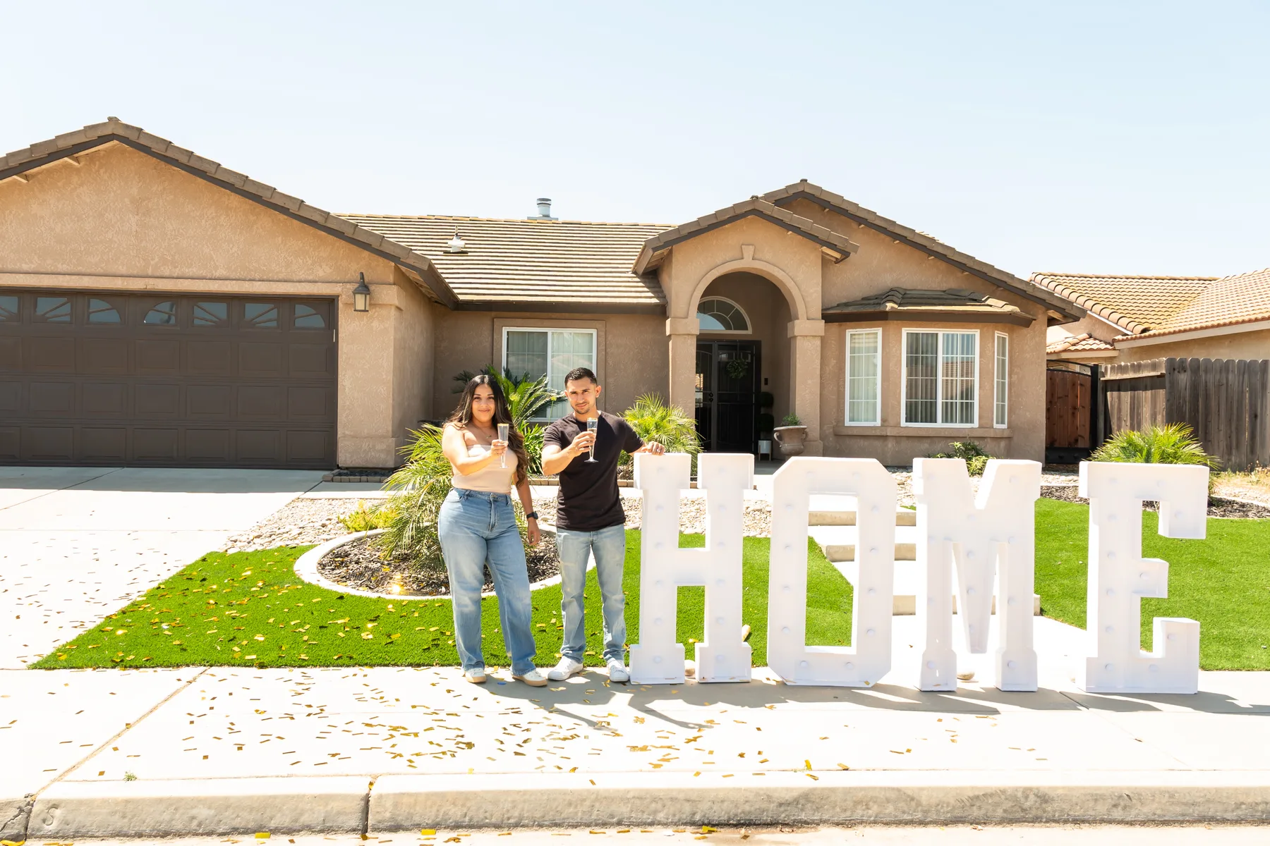 Group stands beside a HOME sign in the front yard.